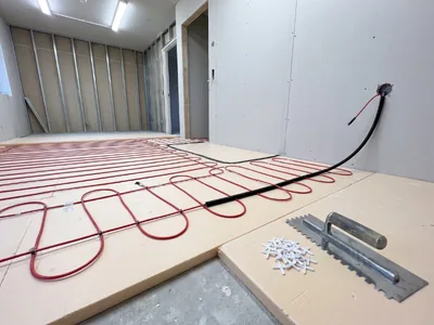 Electric underfloor heating cable in uniform loops on insulation boards, the factory connection of the heating cable to the cold supply end always remains in the adhesive layer of the floor, not in the wall.