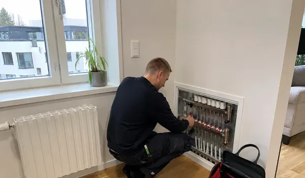 Balancing the heating system, the plumber adjusts the valves of the distribution manifold in the open manifold cabinet, the inflow temperature of the Tallinn district heating network rises as the outside air cools.
