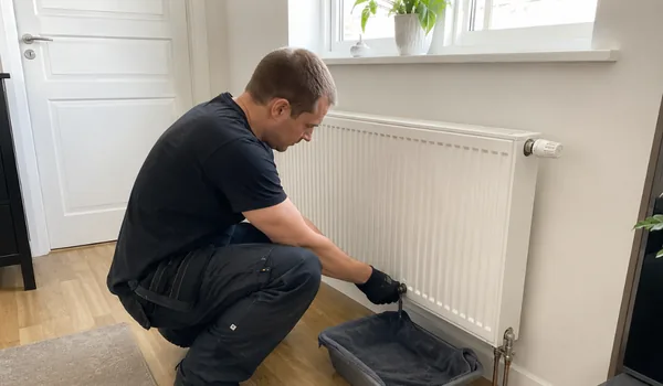 Radiator repair, the plumber works on the lower connection of the panel radiator above the tray, the thermostat head is always installed horizontally, because the upright head gets caught in the warm air rising from the radiator and closes the valve too early.