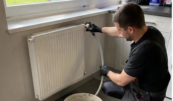 Flushing the radiators, the hose connected to the radiator valve directs the water into the bucket, the hose is screwed onto the valve by hand, not with pliers, so that the brass thread remains intact.