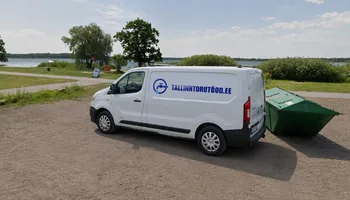A white van with a water tap, a circular logo and the words TALLINNTORUTOOD.EE on the shore of Maardu lake on a dirt road, with a lake mirror and riparian trees behind, Maardu received city rights in 1980.