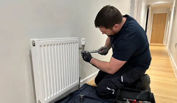 Thermostat valve replacement, the plumber turns the radiator valve with a wrench, the new thermostat heads have a gas-filled sensor and respond accurately to the room temperature.